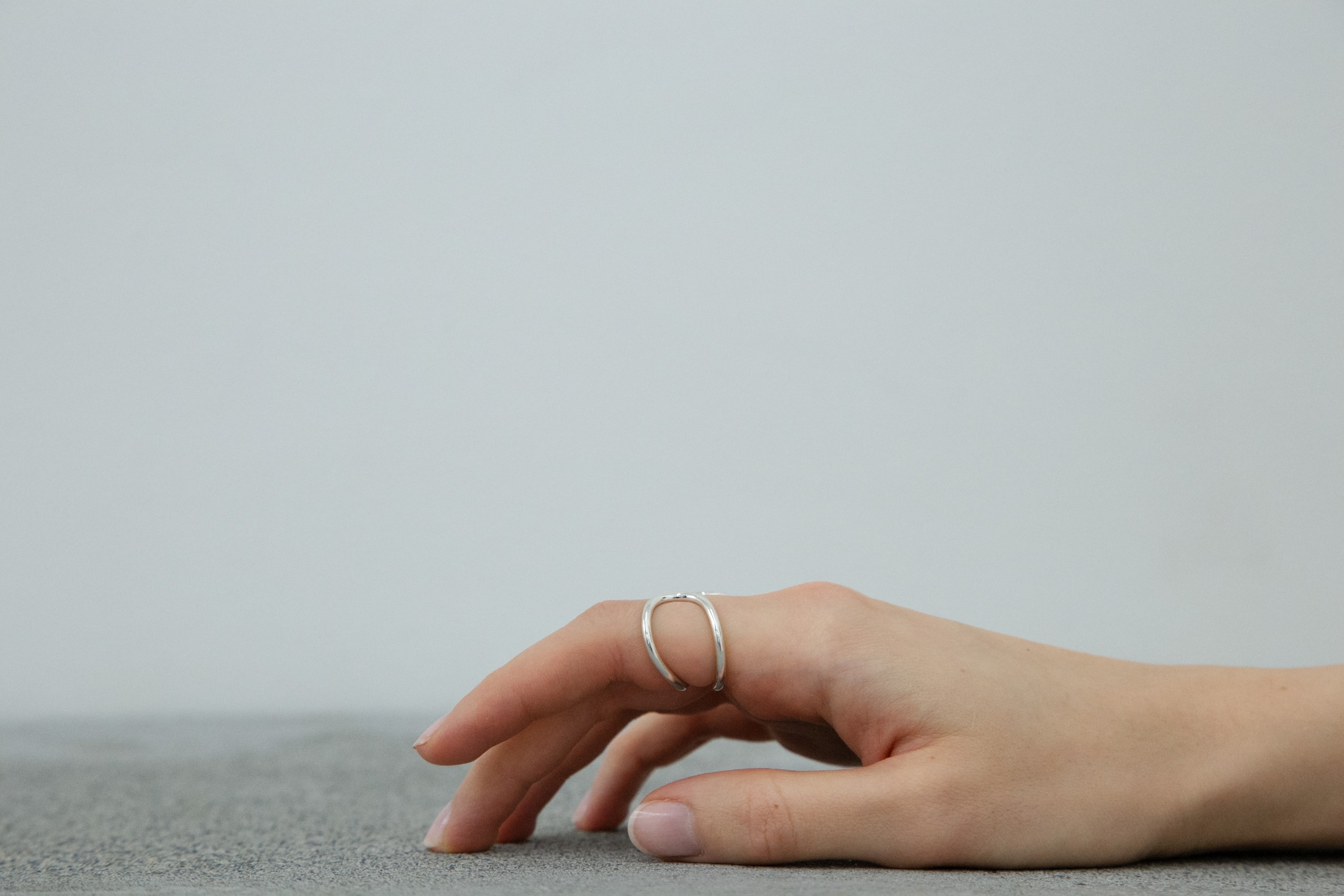 A hand resting on concrete wearing a NEYA ring